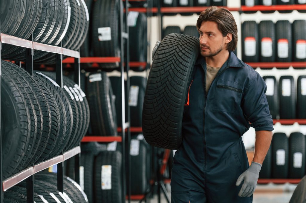 Moving the tire. Man is in the tire fitting car service